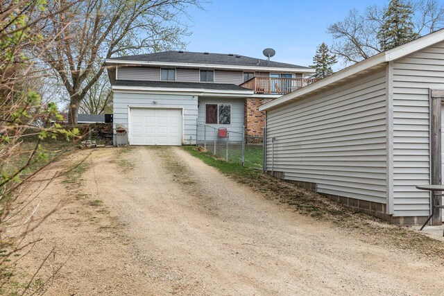 exterior space with a garage, fence, a balcony, a shingled roof, and driveway