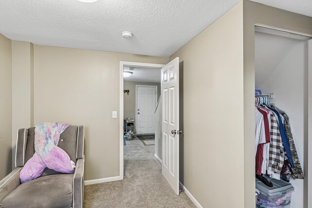 hallway with carpet flooring, a textured ceiling, and baseboards