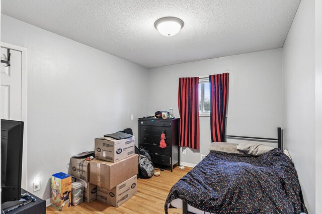 bedroom with a textured ceiling and wood finished floors