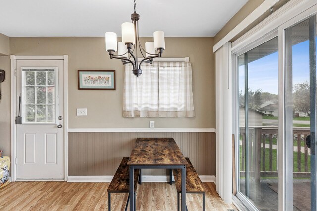 dining room with wainscoting, wood finished floors, a chandelier, and a healthy amount of sunlight