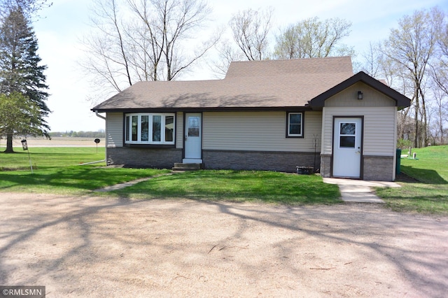 ranch-style home featuring entry steps, stone siding, and a front yard