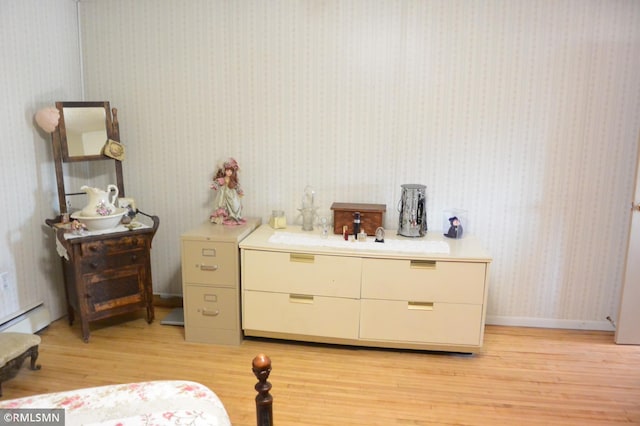 bedroom with wallpapered walls, light wood-type flooring, and a baseboard radiator