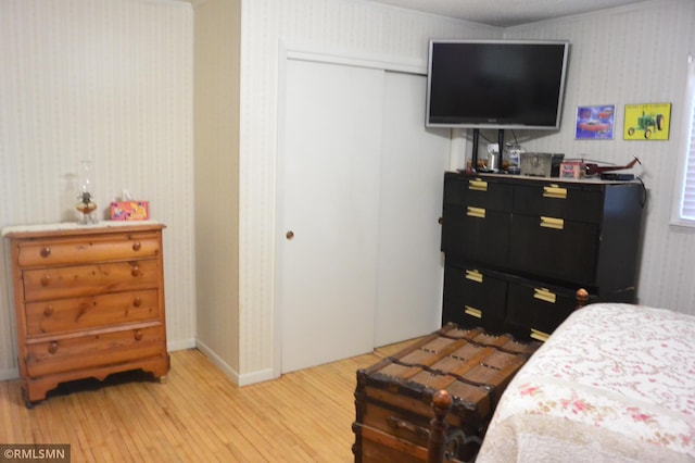 bedroom featuring baseboards, a closet, light wood-type flooring, and wallpapered walls