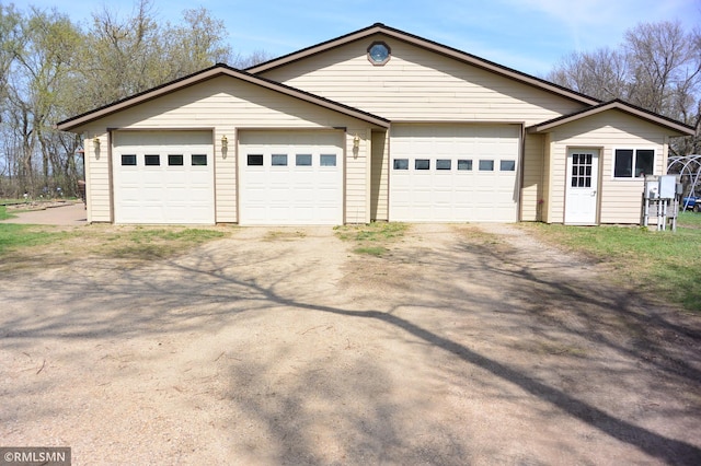 view of front of house featuring dirt driveway, an outbuilding, and a detached garage
