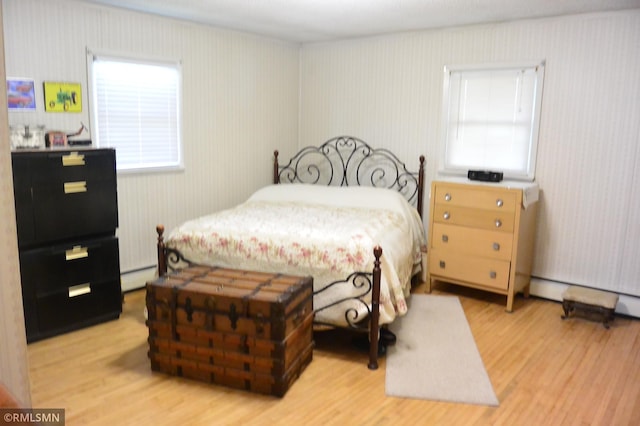bedroom with baseboard heating and wood finished floors