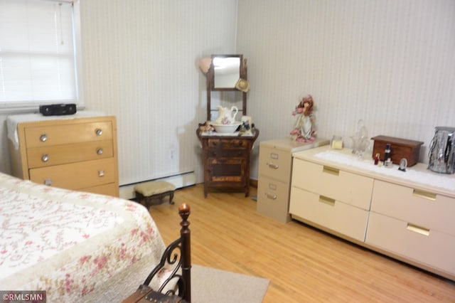 bedroom with a baseboard radiator and light wood-style floors