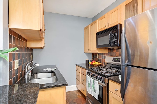 kitchen featuring light brown cabinets, baseboards, a sink, backsplash, and stainless steel appliances
