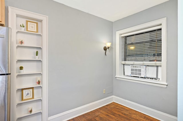 unfurnished room featuring cooling unit, baseboards, and dark wood-type flooring