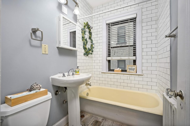 full bathroom with a shower, wood finished floors, toilet, a washtub, and a sink