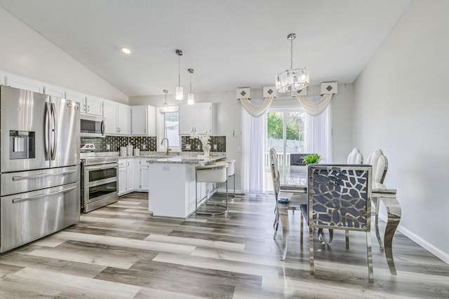 18095 Exeter Pl, Farmington, MN 55024 - kitchen featuring stainless steel appliances, a sink, light wood-style floors, white cabinets, and lofted ceiling