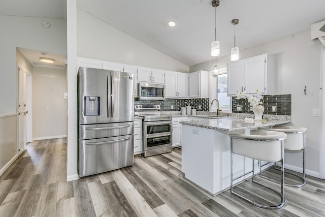 18095 Exeter Pl, Farmington, MN 55024 - kitchen featuring stainless steel appliances, a sink, a peninsula, white cabinetry, and lofted ceiling