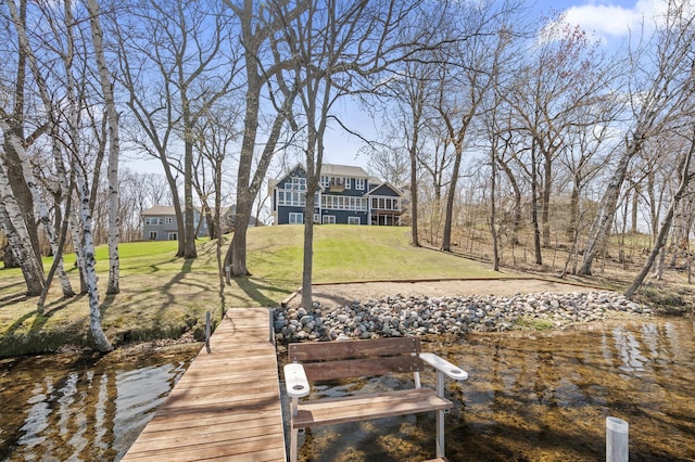 view of dock with a lawn and a water view