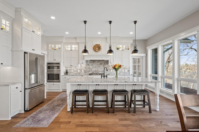 kitchen with decorative backsplash, white cabinetry, and appliances with stainless steel finishes