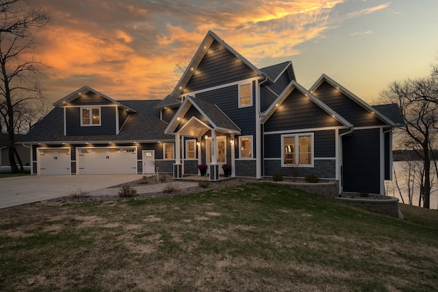 craftsman-style house with a lawn, an attached garage, driveway, and stone siding