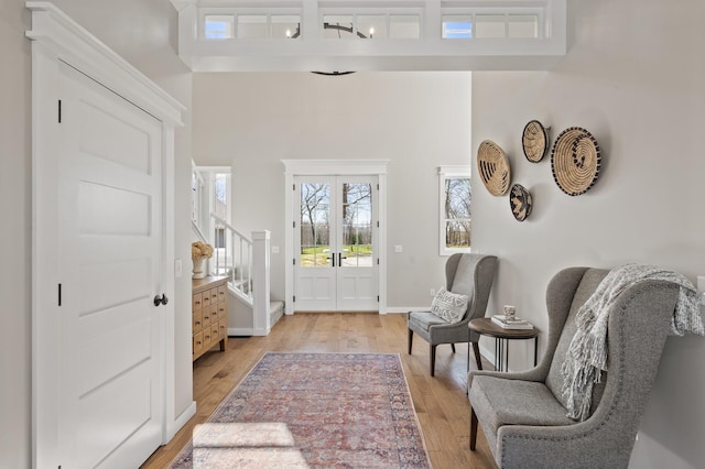 foyer with light wood-type flooring, baseboards, stairway, and french doors