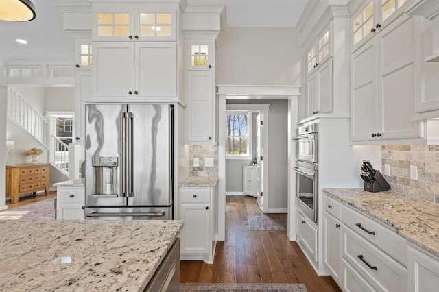kitchen with white cabinets, stainless steel appliances, dark wood finished floors, and tasteful backsplash