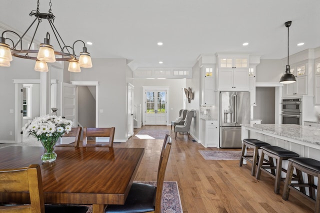 dining space featuring baseboards, light wood finished floors, and recessed lighting