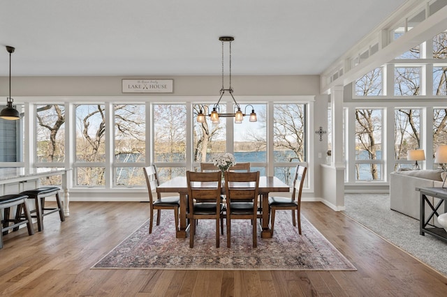 dining area featuring baseboards, wood finished floors, and a notable chandelier