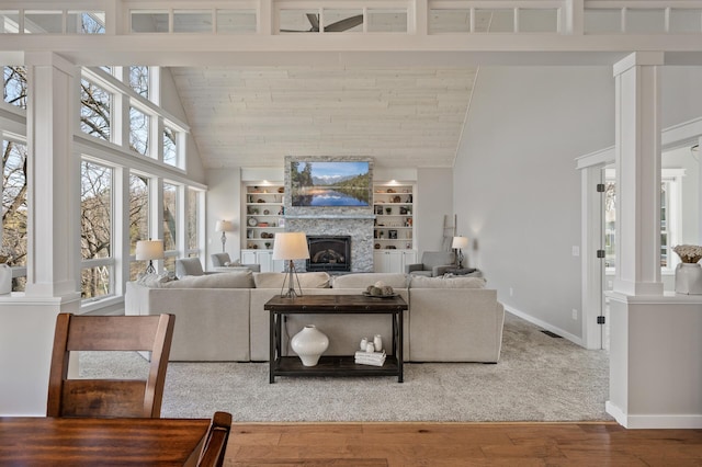 living room featuring a healthy amount of sunlight, high vaulted ceiling, a fireplace, and ornate columns