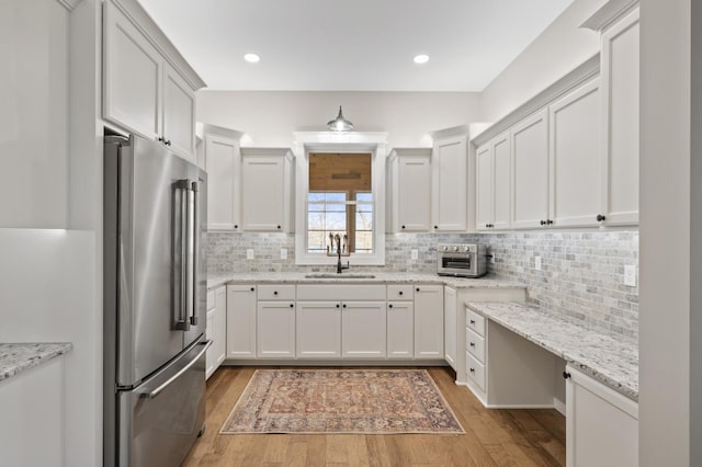 kitchen with a sink, decorative backsplash, light wood-style flooring, and high end fridge
