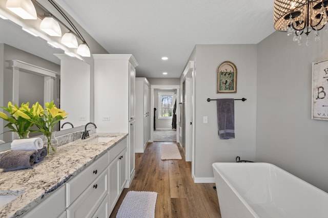 full bathroom with vanity, recessed lighting, baseboards, a freestanding tub, and wood finished floors
