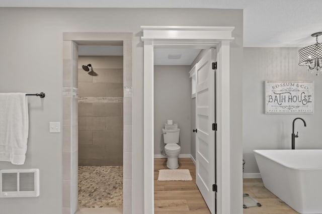 bathroom featuring visible vents, an inviting chandelier, wood finished floors, toilet, and a tile shower
