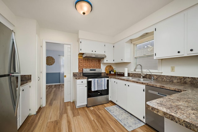 kitchen with a sink, light wood-style flooring, dark countertops, and stainless steel appliances
