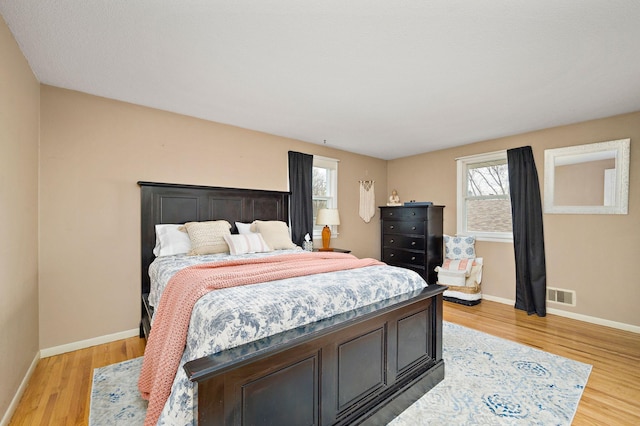 bedroom with baseboards, visible vents, and light wood finished floors