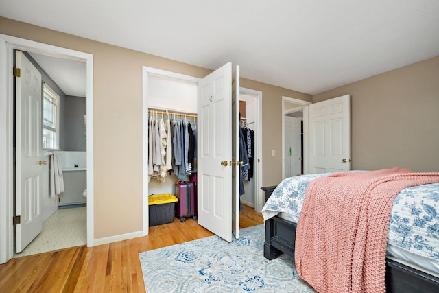 bedroom with a closet, light wood finished floors, ensuite bathroom, and baseboards
