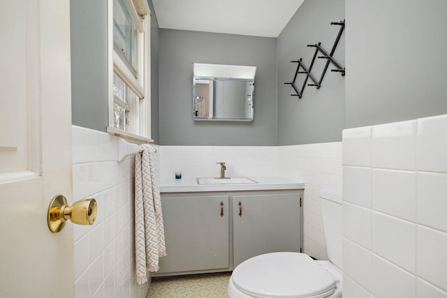 bathroom with toilet, tile walls, a wainscoted wall, and vanity