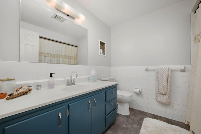 bathroom with visible vents, tile walls, vanity, tile patterned floors, and toilet