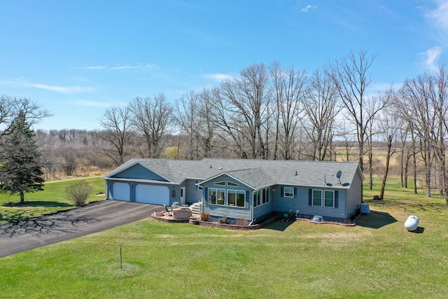 single story home featuring driveway, a shingled roof, an attached garage, and a front yard