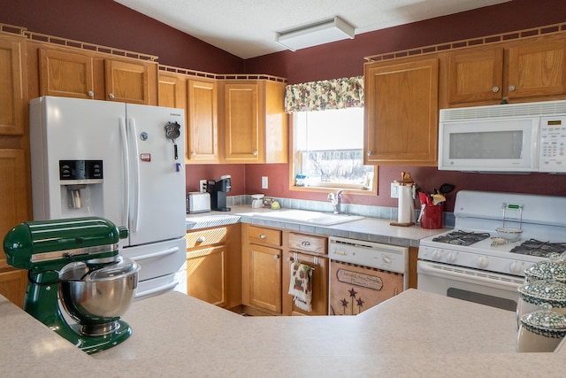 kitchen with a sink, brown cabinetry, white appliances, and light countertops