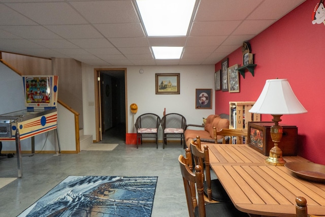 interior space with baseboards, a drop ceiling, stairway, and concrete flooring