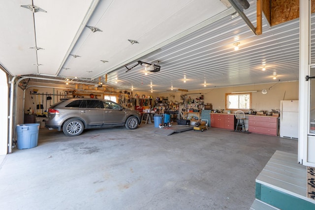 garage with freestanding refrigerator, a workshop area, and a garage door opener