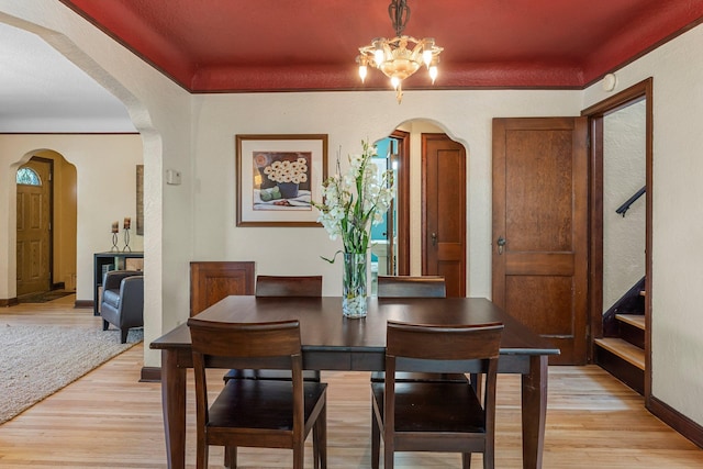 dining room featuring light wood-type flooring, arched walkways, and a chandelier