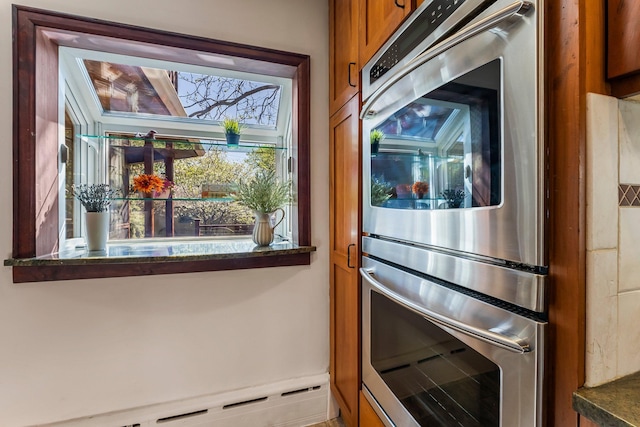 kitchen with brown cabinets, stainless steel double oven, and a baseboard radiator