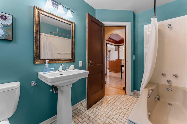 bathroom with baseboards, shower / tub combo, toilet, tile patterned flooring, and a sink
