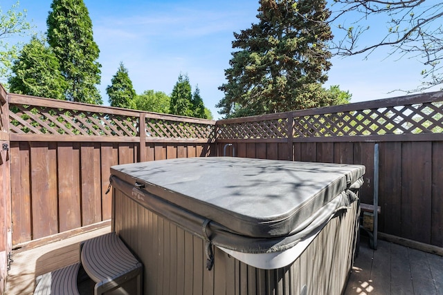 wooden deck with a hot tub and fence