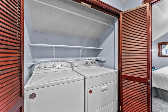 laundry area featuring washing machine and dryer and a textured wall