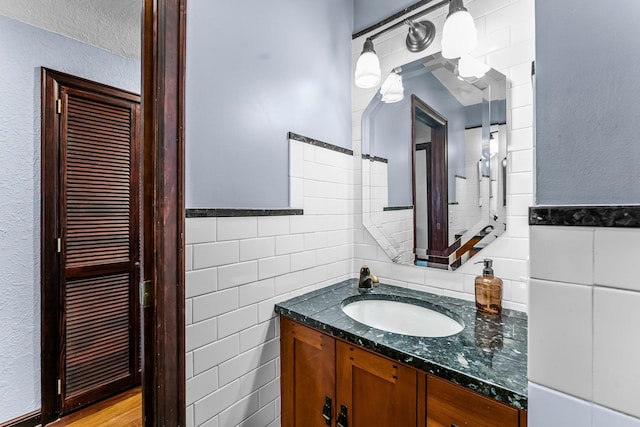 bathroom featuring tile walls, vanity, and a wainscoted wall