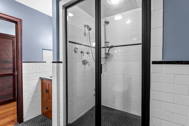 full bathroom with tile walls, a shower stall, wainscoting, and tile patterned flooring