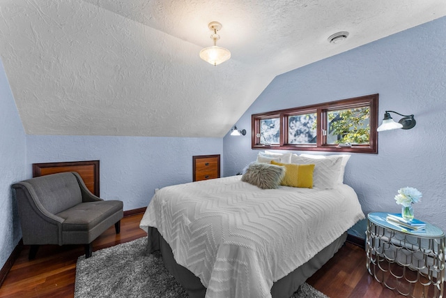 bedroom featuring a textured wall, a textured ceiling, lofted ceiling, wood finished floors, and baseboards