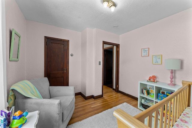 bedroom with wood finished floors, baseboards, and a textured ceiling