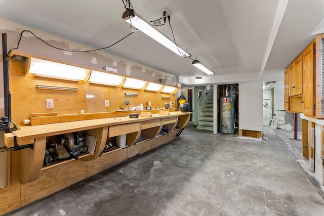 basement featuring gas water heater, a workshop area, and stairway