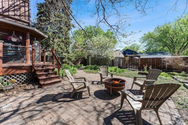 view of patio featuring a fenced backyard, a fire pit, and a wooden deck