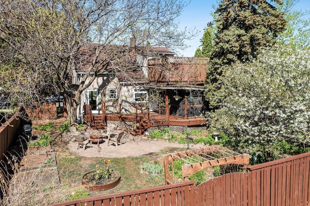 rear view of property featuring an outdoor fire pit, a deck, fence, a patio, and a chimney