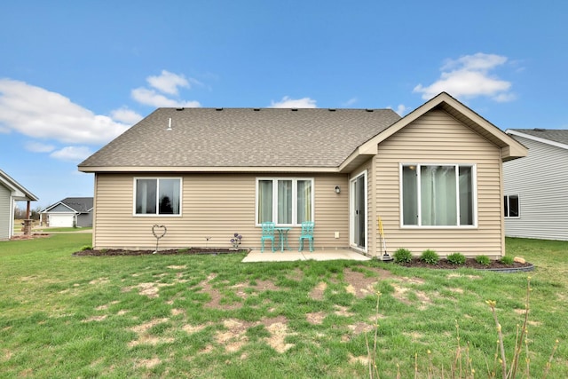 rear view of house featuring a yard, a shingled roof, and a patio area