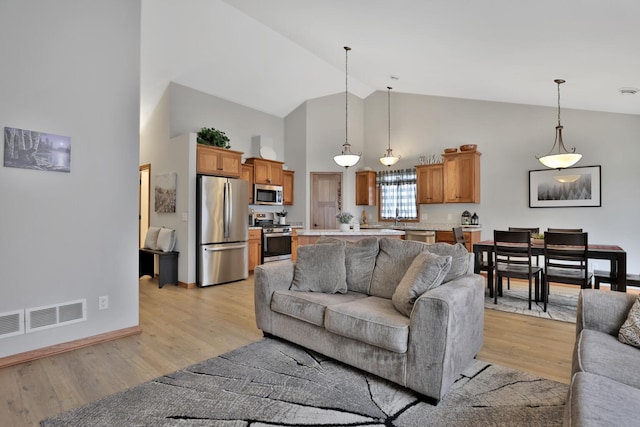 living area featuring high vaulted ceiling, visible vents, baseboards, and light wood-style floors