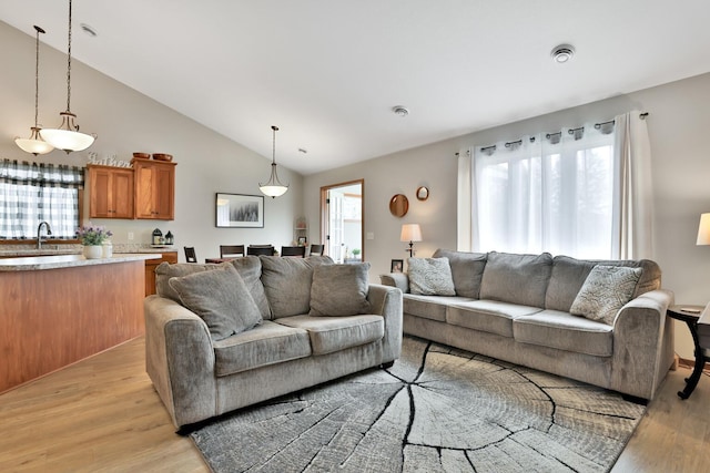 living area with light wood-style floors and high vaulted ceiling